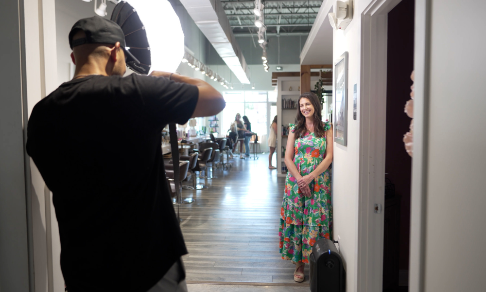 RBV Media A photographer takes a picture of a woman in a colorful dress standing and smiling in a hair salon. Myrtle Beach, Content, Ads, Web, Social, Email