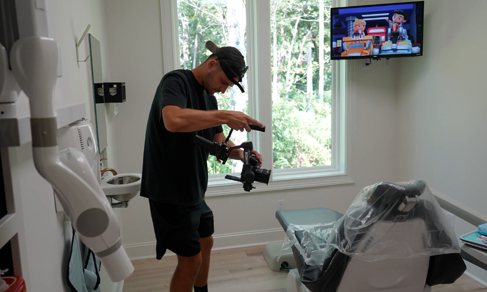 RBV Media A person operates a camera inside a dental office, pointing it at a dental chair; cartoon show plays on a TV mounted on the wall. Myrtle Beach, Content, Ads, Web, Social, Email